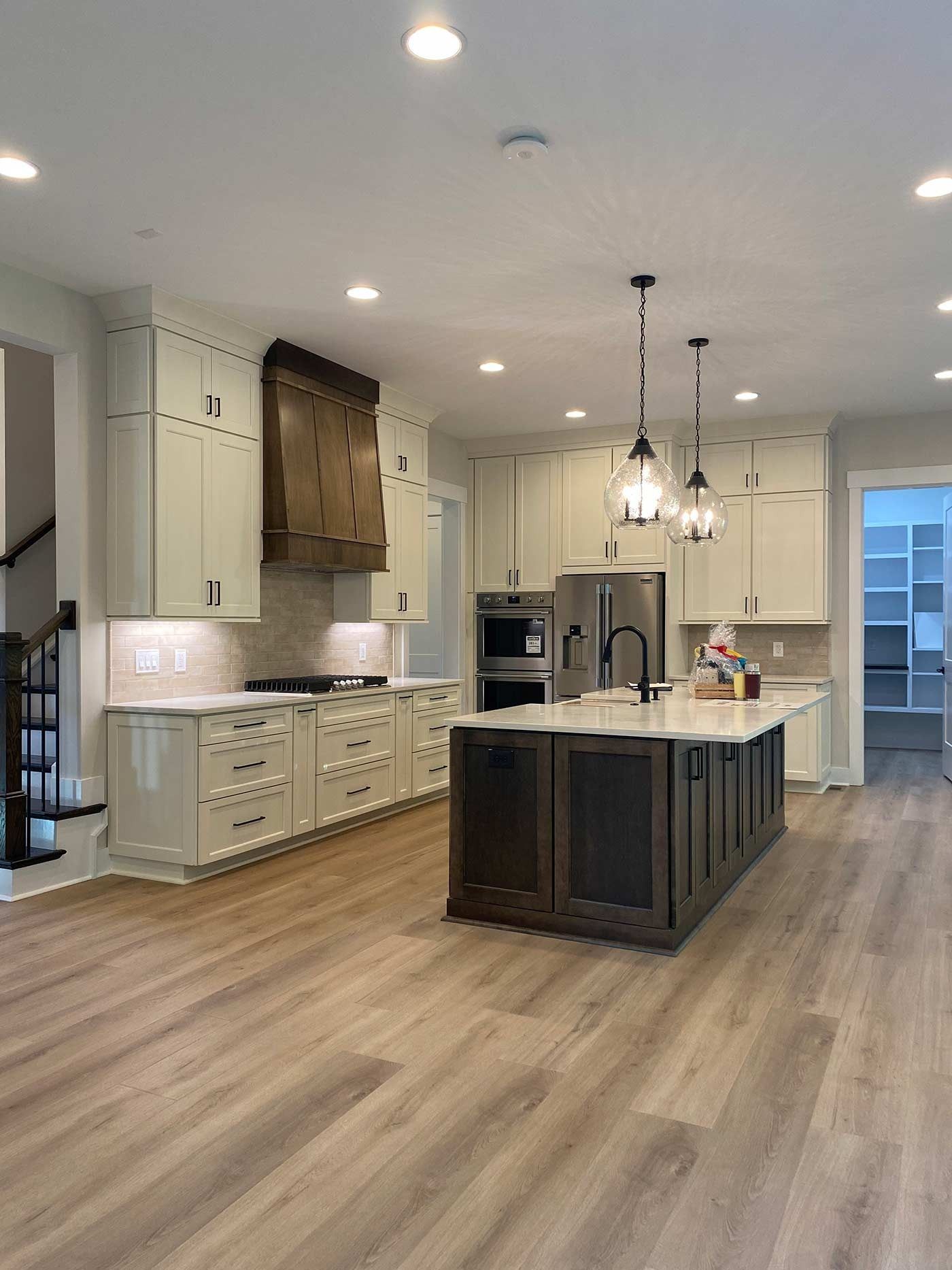 Modern kitchen with cream cabinets, large island, pendant lights, and wood flooring
