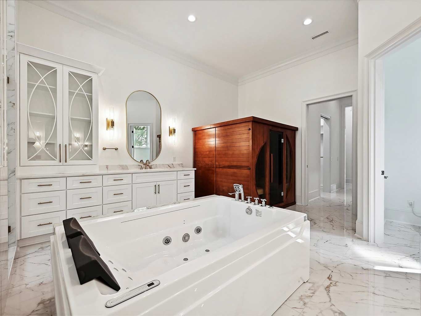 Bright white bathroom with a freestanding jacuzzi tub, double vanity, armoire, and glass shower.
