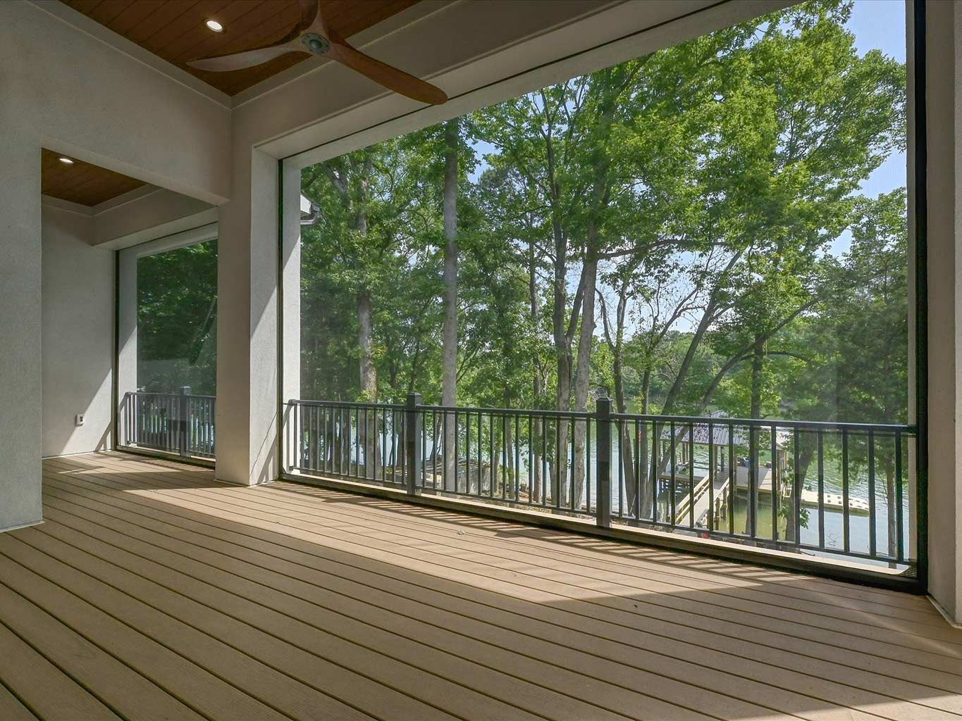 Covered wooden deck overlooking trees and water, with railings and open view.