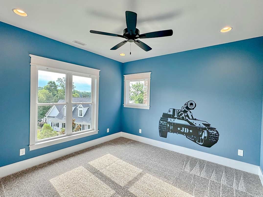 Blue bedroom with two windows, ceiling fan, gray carpet, and a motorcycle wall decal