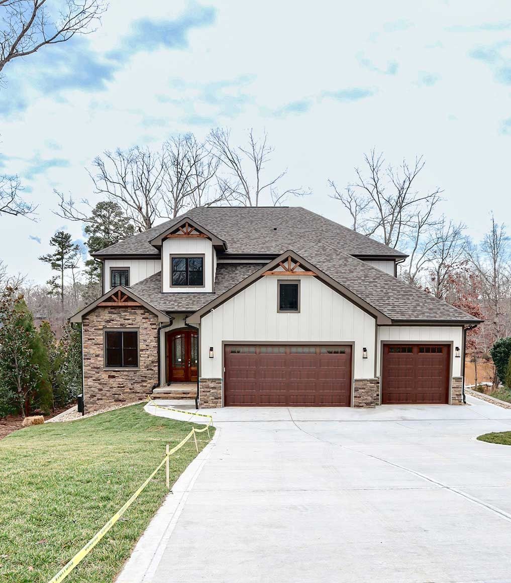 Two-story suburban house with brick and white siding, brown garage doors, and a concrete driveway