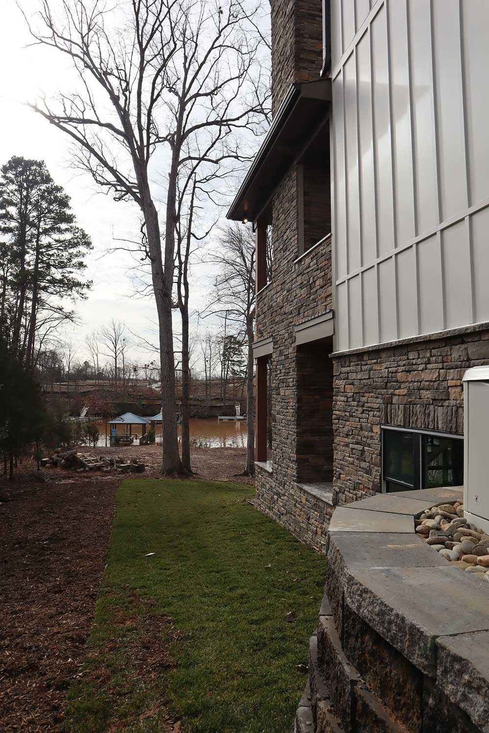 Apartment building exterior with brick and metal siding beside a grassy path and bare trees