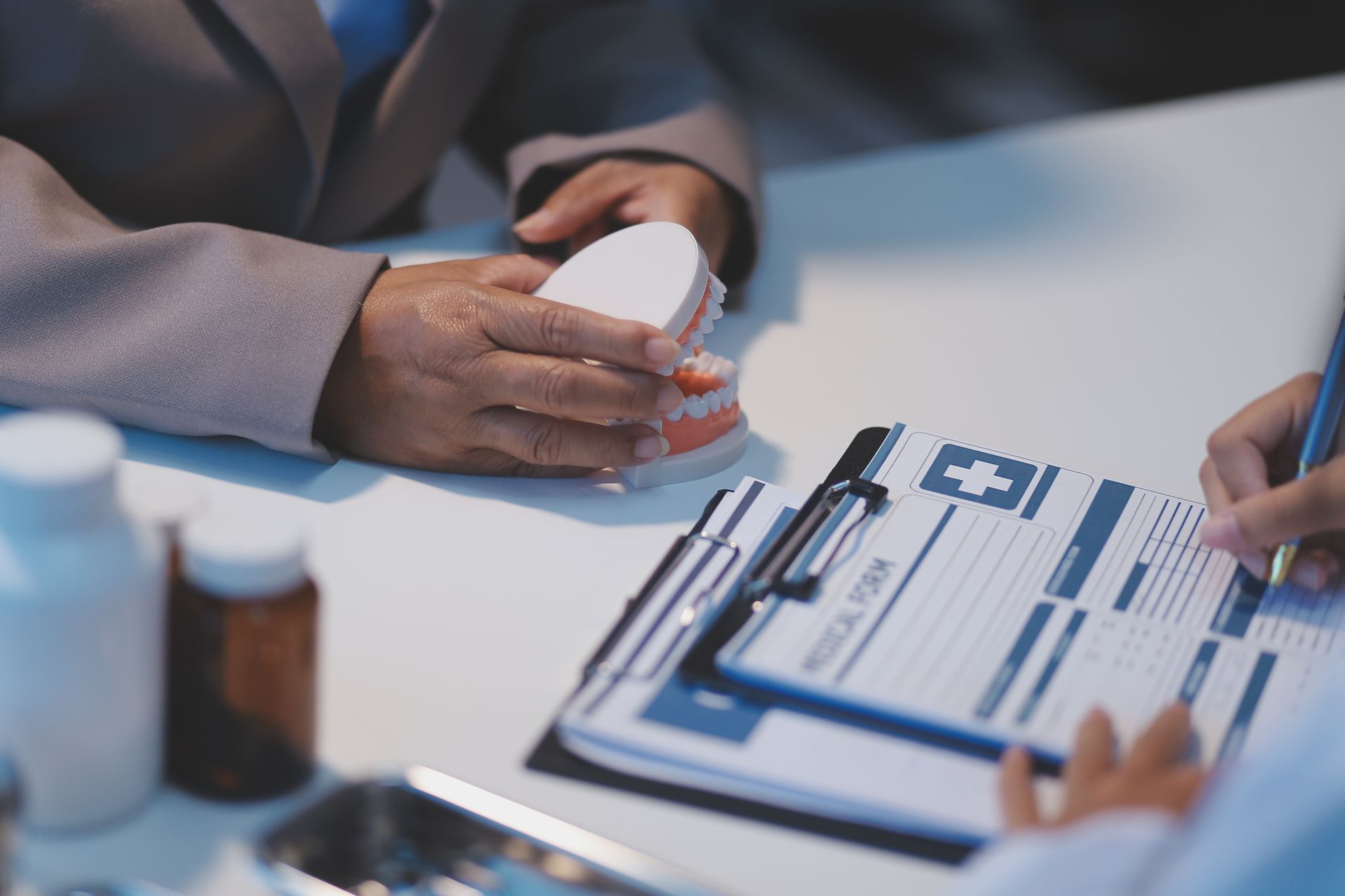 Dentist consulting patient about dentures, filling out medical form.