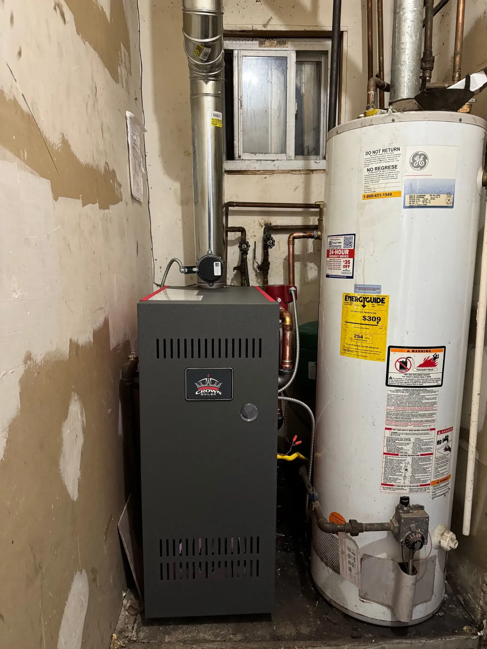 Gray furnace and white water heater in a utility room with a small window.