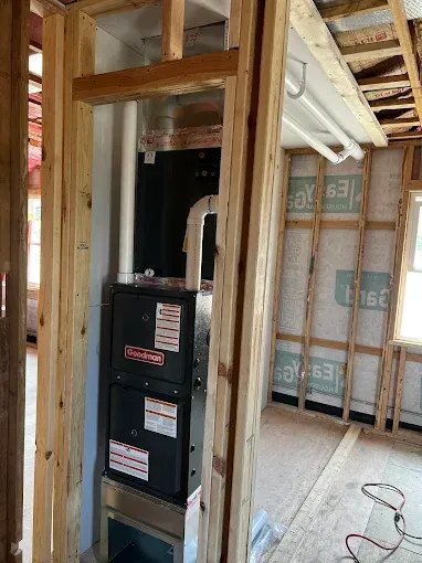 New furnace installation in a framed wall, unfinished interior.