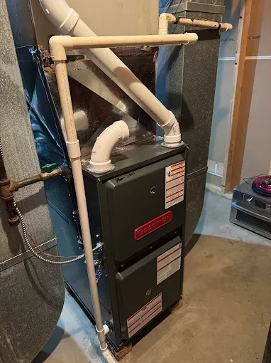 Furnace with white PVC pipes in a utility room.