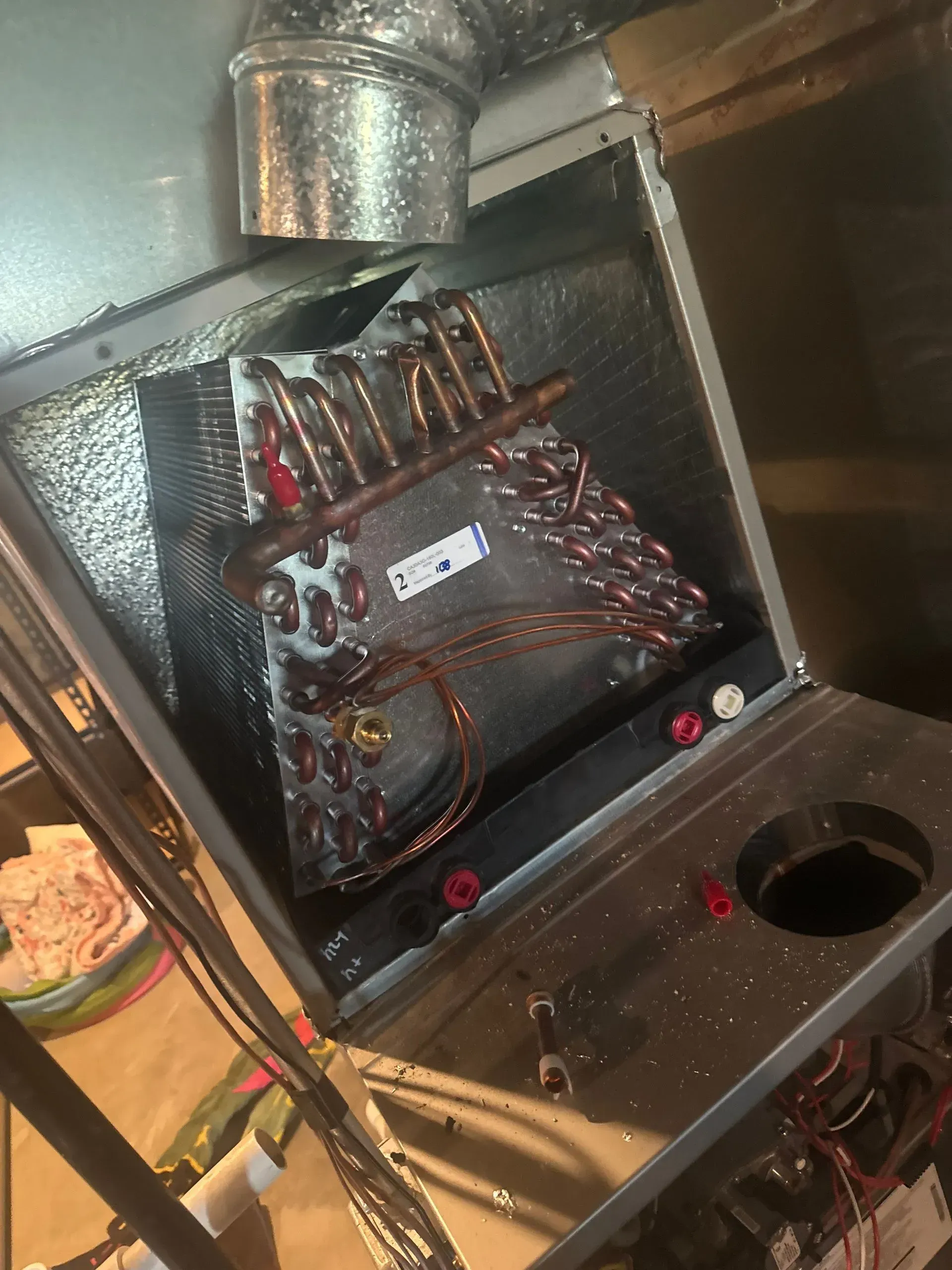 Open air handler box showing copper coils, silver ductwork, and insulation.