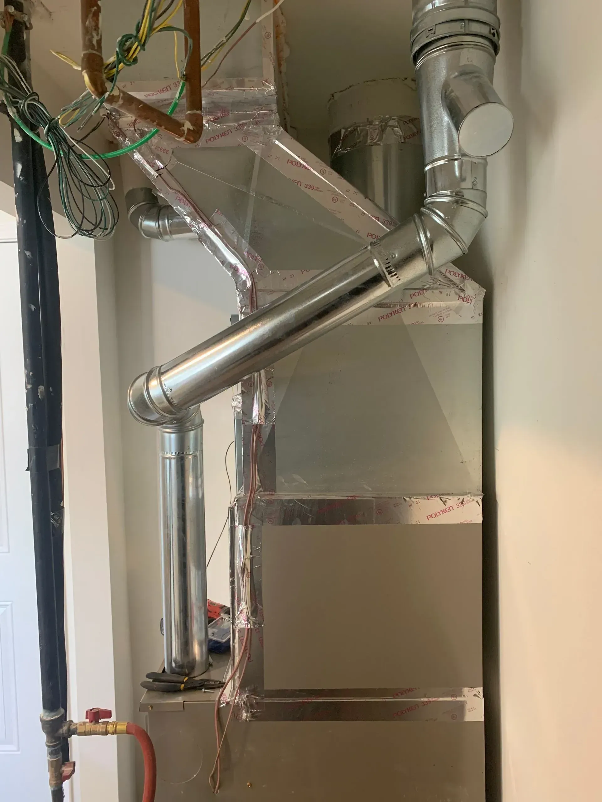 Metallic HVAC system with pipes and vents in a utility room.
