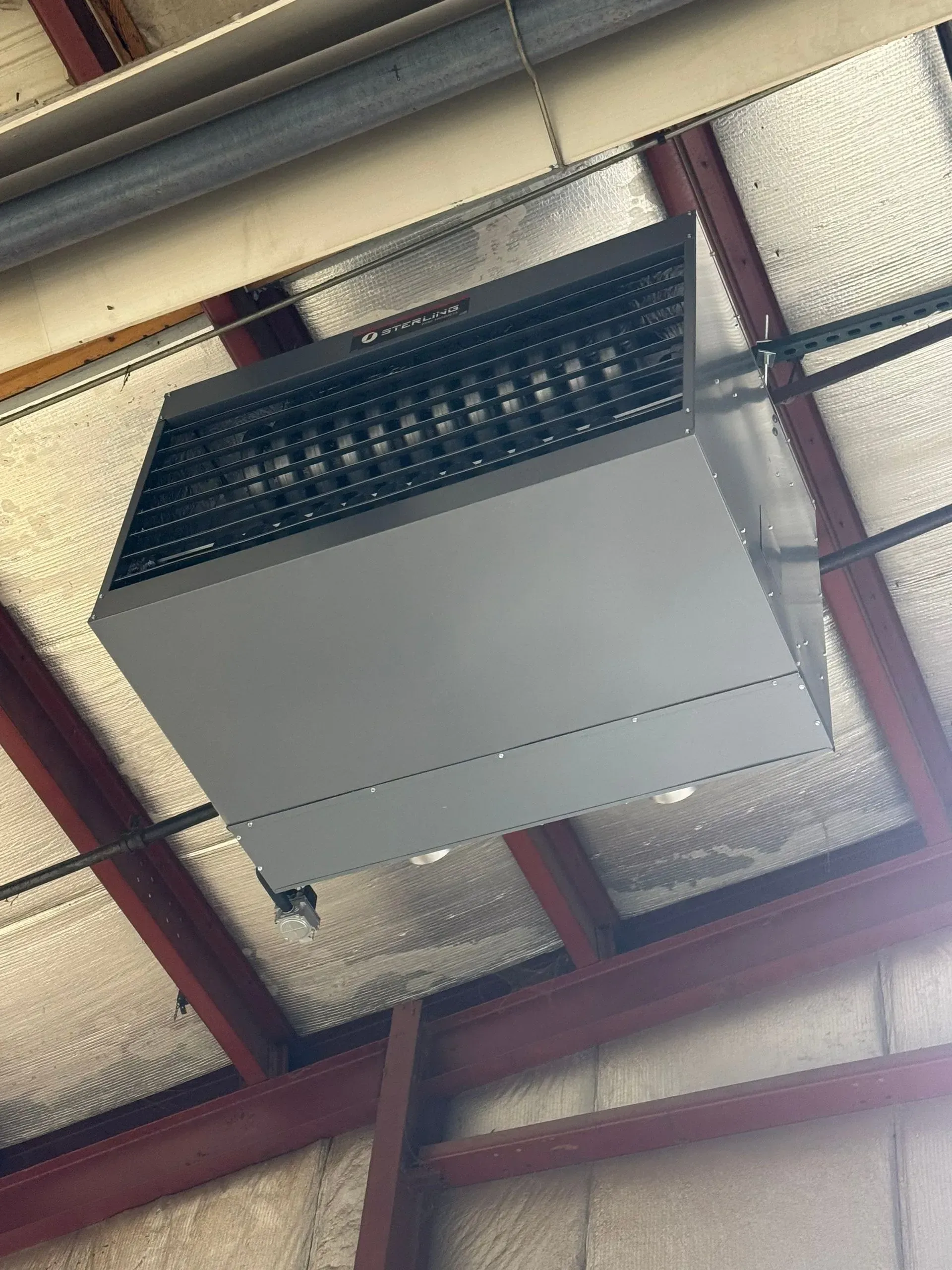 Silver industrial ceiling heater mounted on a metal-framed ceiling.