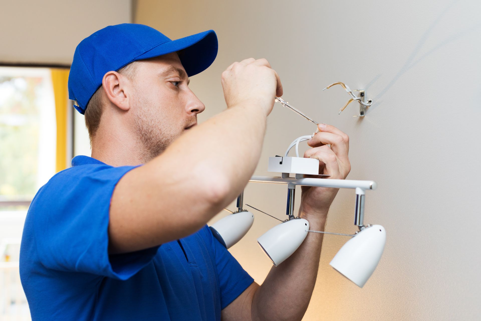 A man is installing a light fixture on a wall.