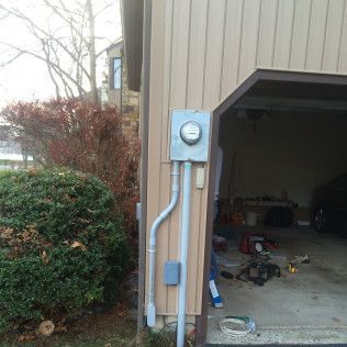 There is a meter on the side of a garage.
