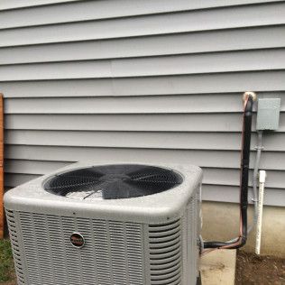 A large air conditioner is sitting outside of a house.