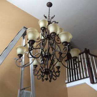A large chandelier is hanging from the ceiling above a staircase