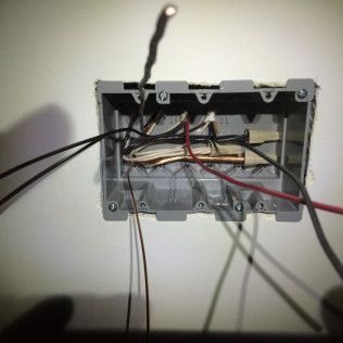 A box with wires coming out of it on a wall.