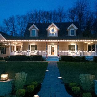 A house is decorated with christmas lights and a wreath on the front porch.