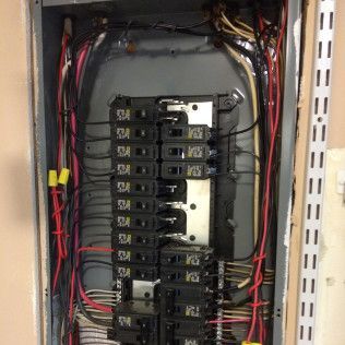 A close up of a electrical panel with a lot of wires coming out of it.