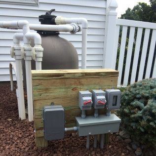 A pool filter is sitting on top of a wooden wall next to a white fence.