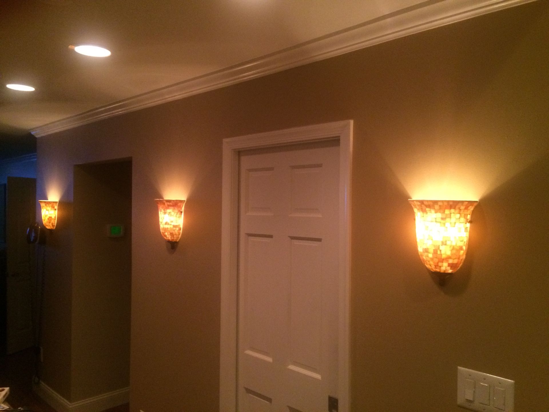 A hallway with a door and two lights on the wall