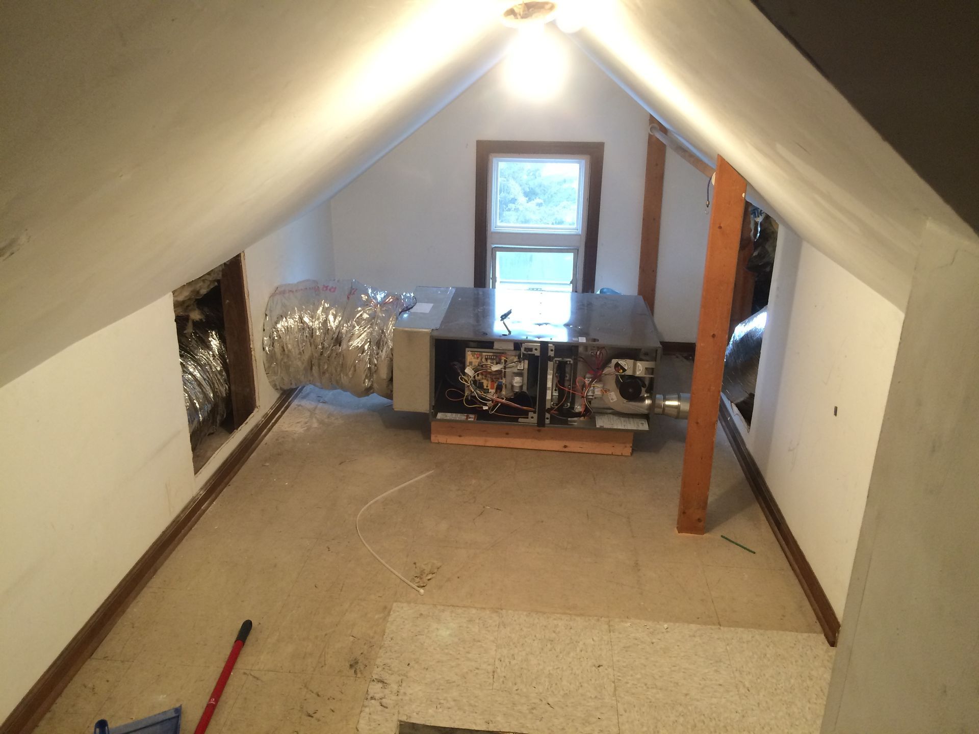 An attic with a ceiling fan and a window