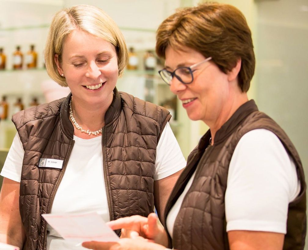Zwei Frauen schauen auf ein Stück Papier und lächeln