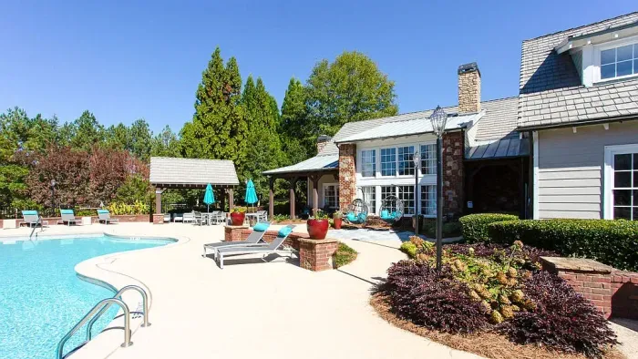 Poolside patio with lounge chairs beside a house, trees, and a bright blue swimming pool at Preserve at Mill Creek in Buford