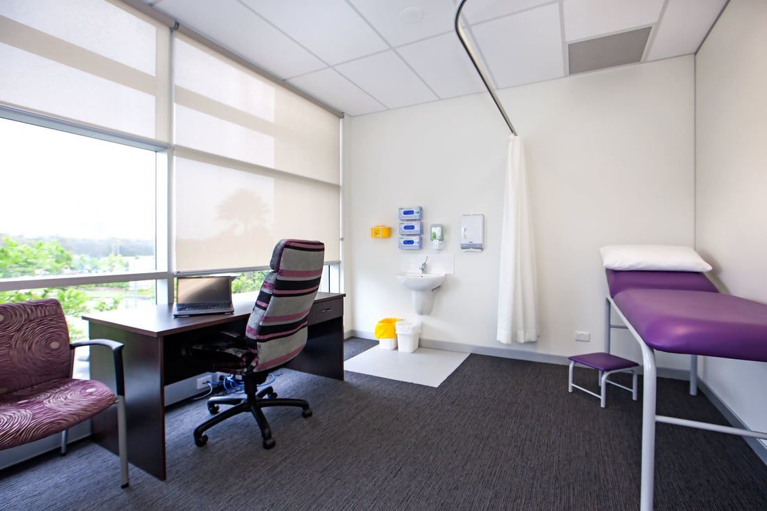 A doctor 's office with a desk and a purple bed