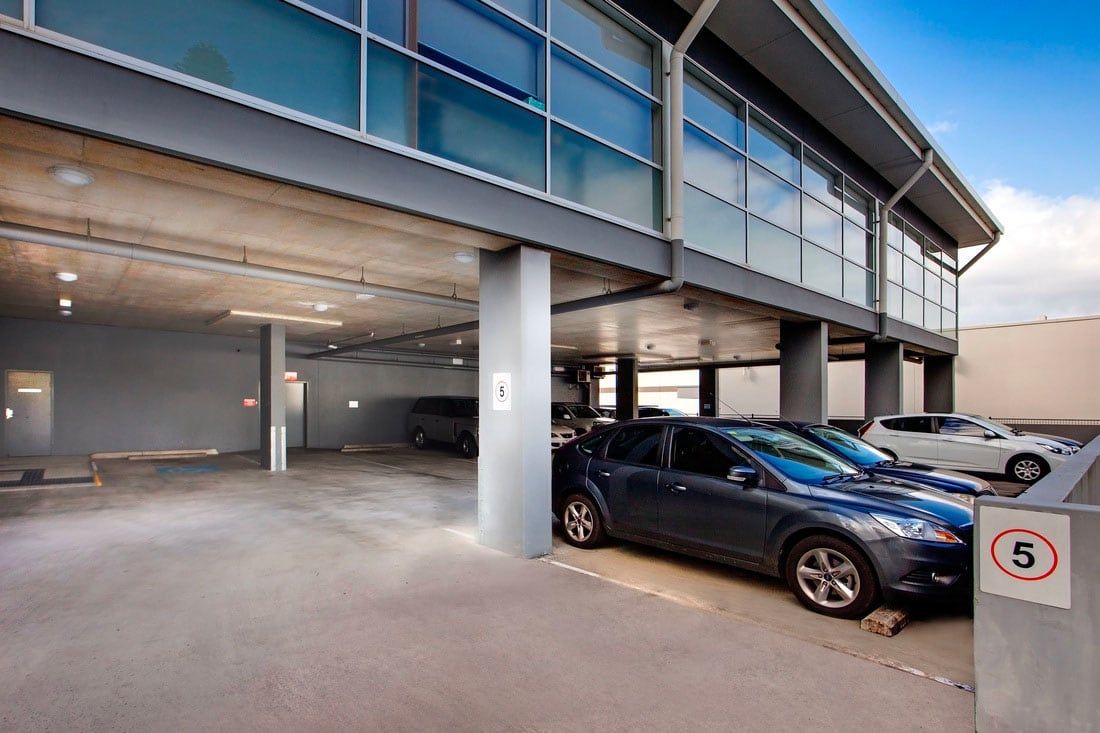 A blue car is parked in a parking lot in front of a building.