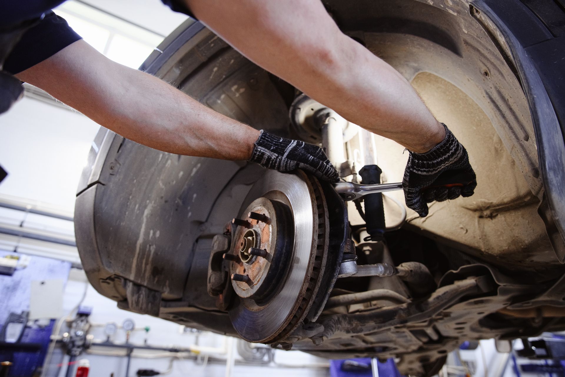 Mechanic working on car's brake system, using a wrench. 