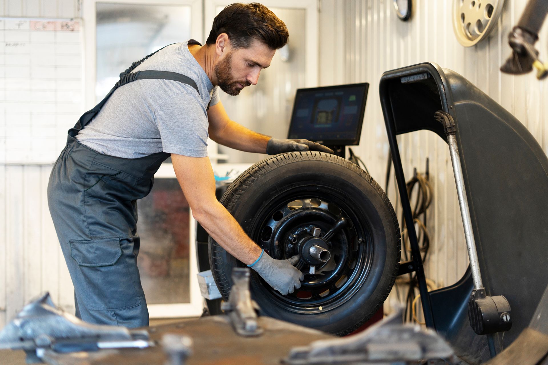 Mechanic balancing a car tire with a machine in a workshop.