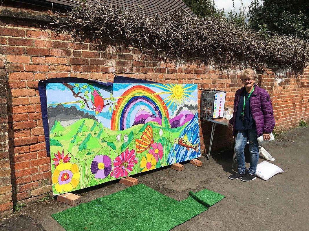 a woman is standing in front of a large painting on a brick wall .