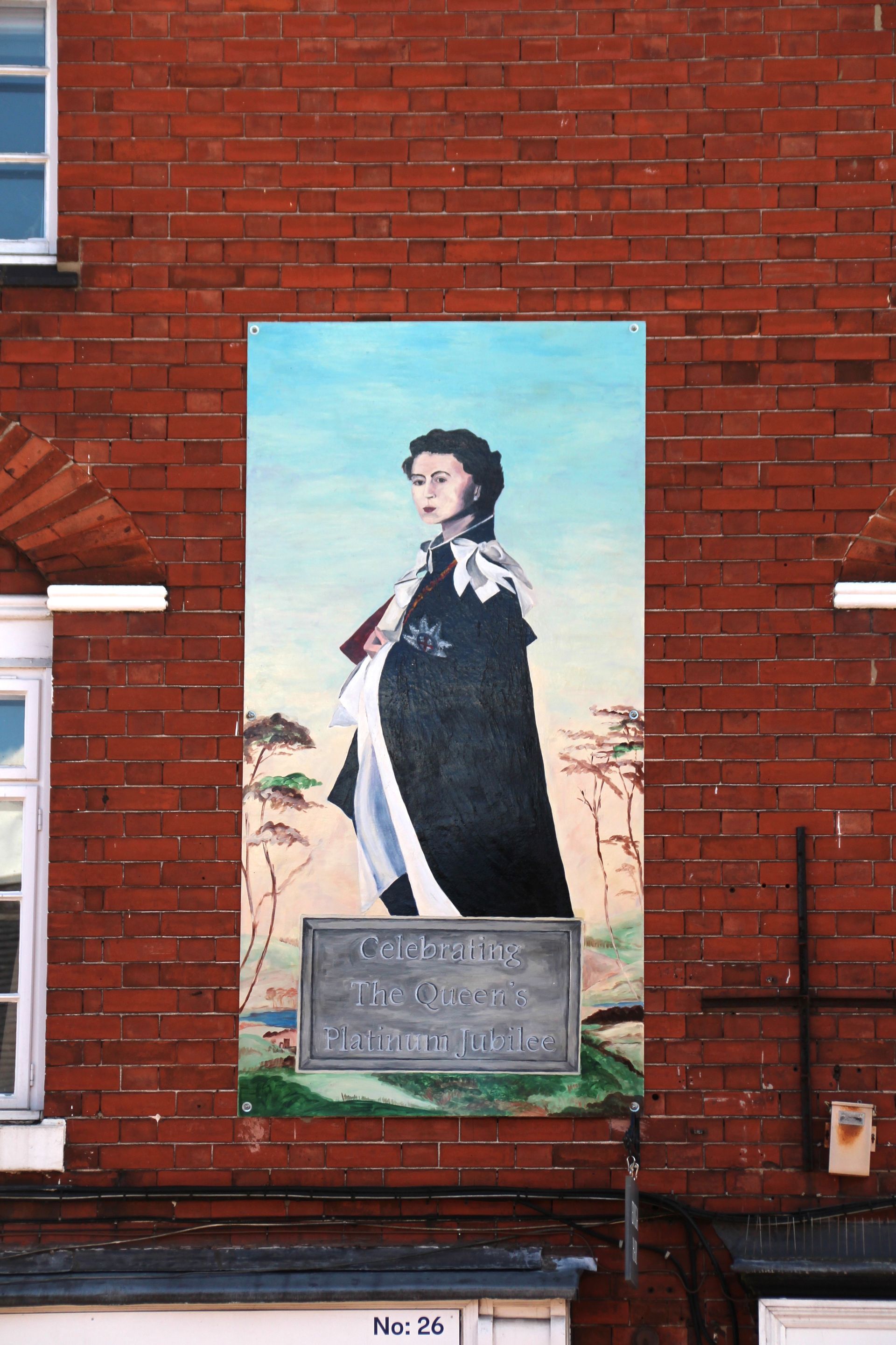 a brick wall with a painting of the queen on it