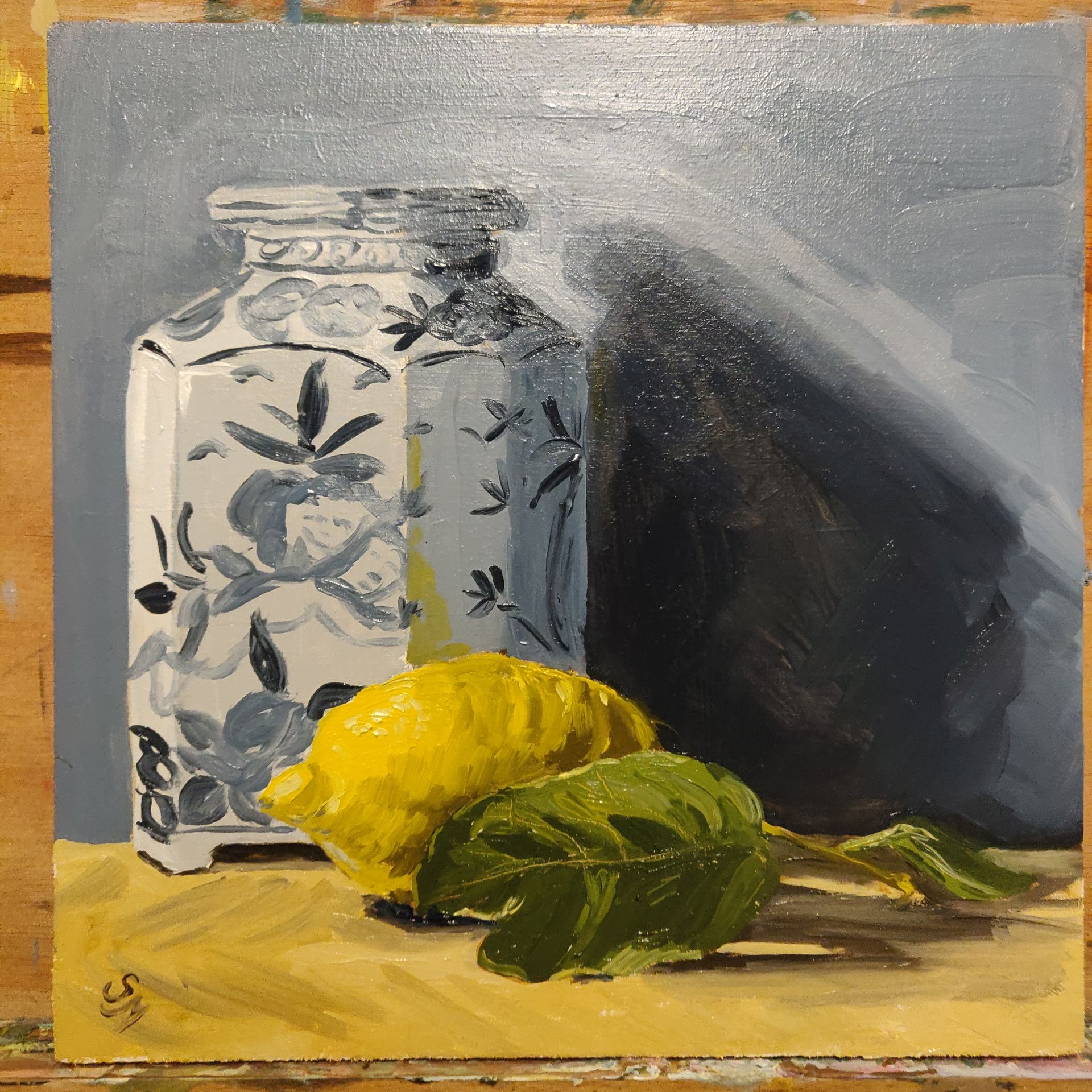 A painting of a vase with a lemon and leaves