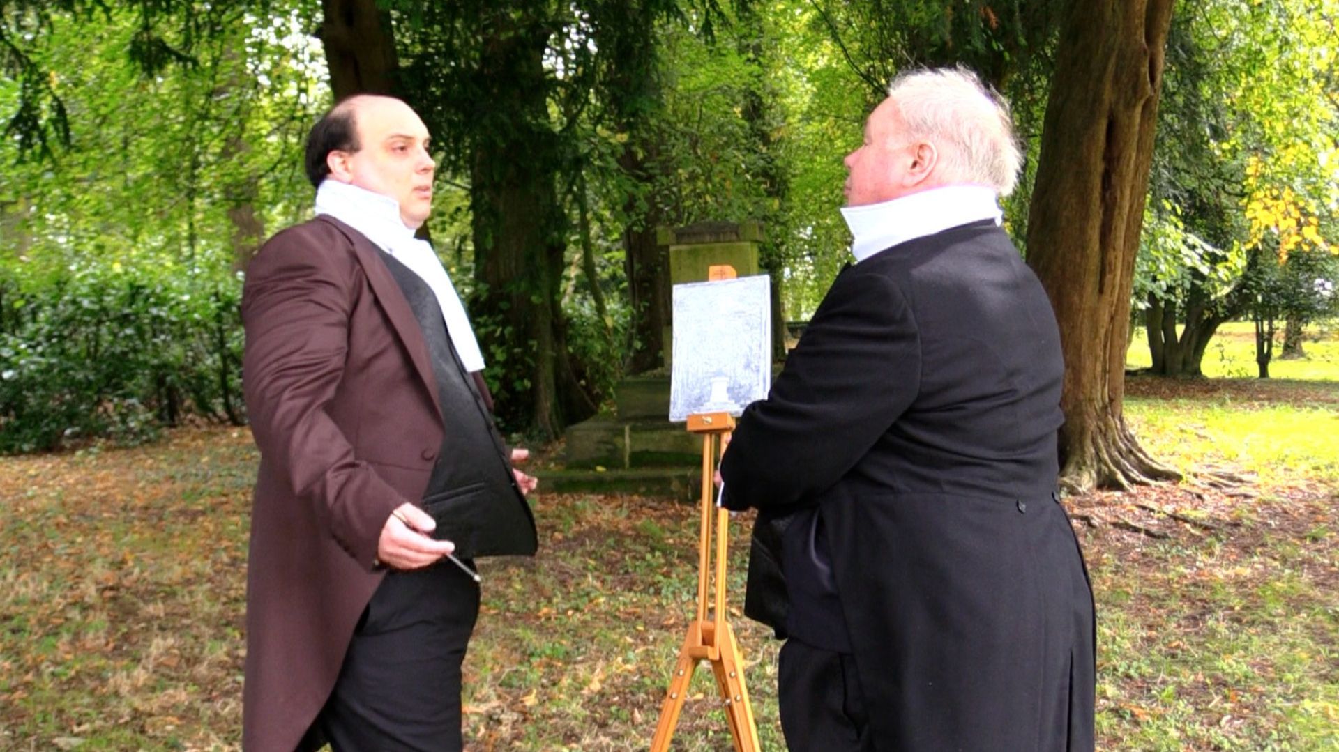 two men in suits are standing next to each other in a park .