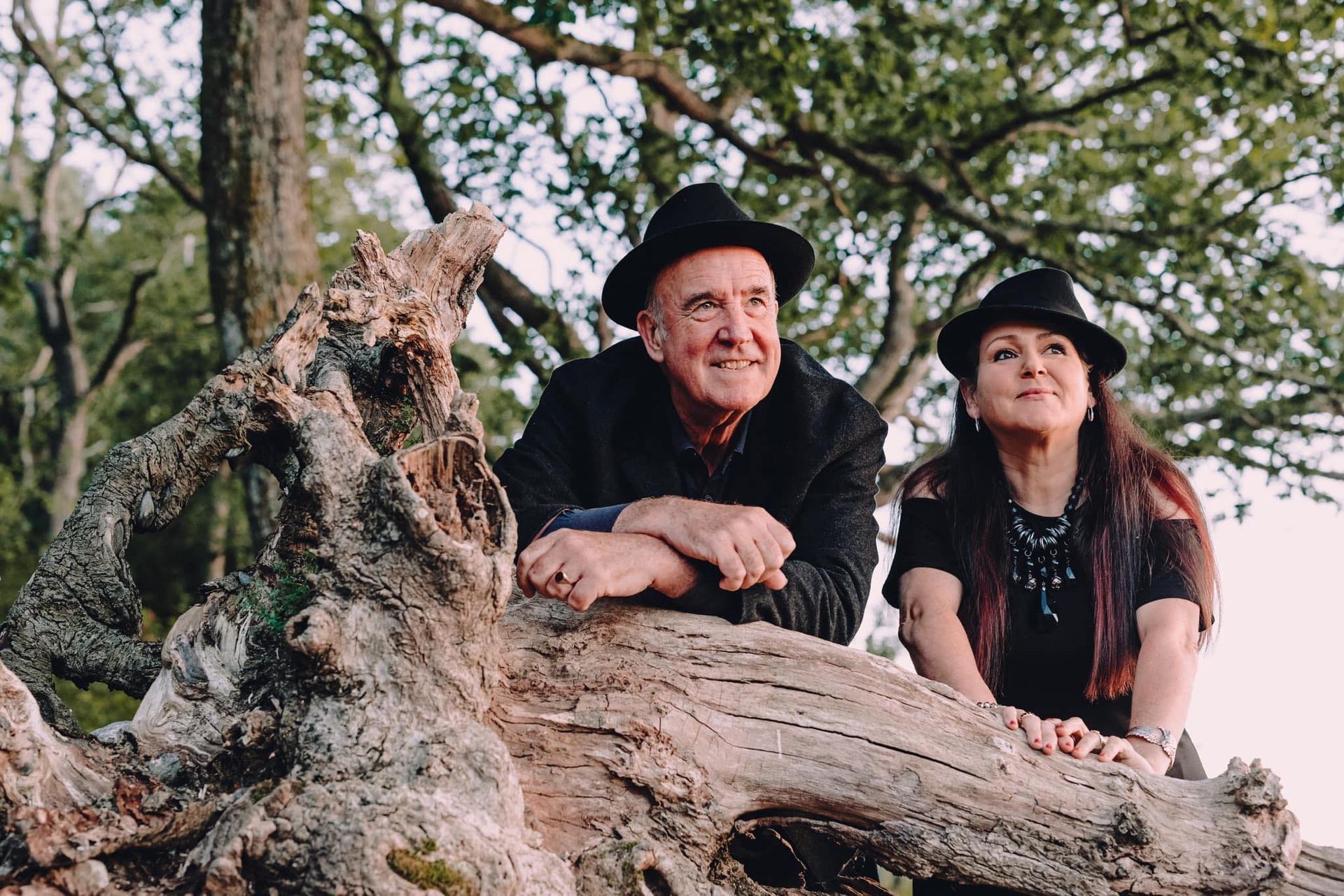 a man and a woman are sitting on a tree trunk .