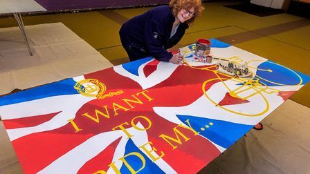 a woman is painting a large british flag on canvas