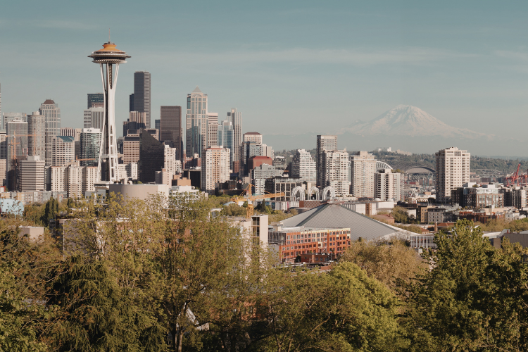 The Seattle skyline featuring the Space Needle, surrounded by urban buildings with Mount Rainier visible in the distance.