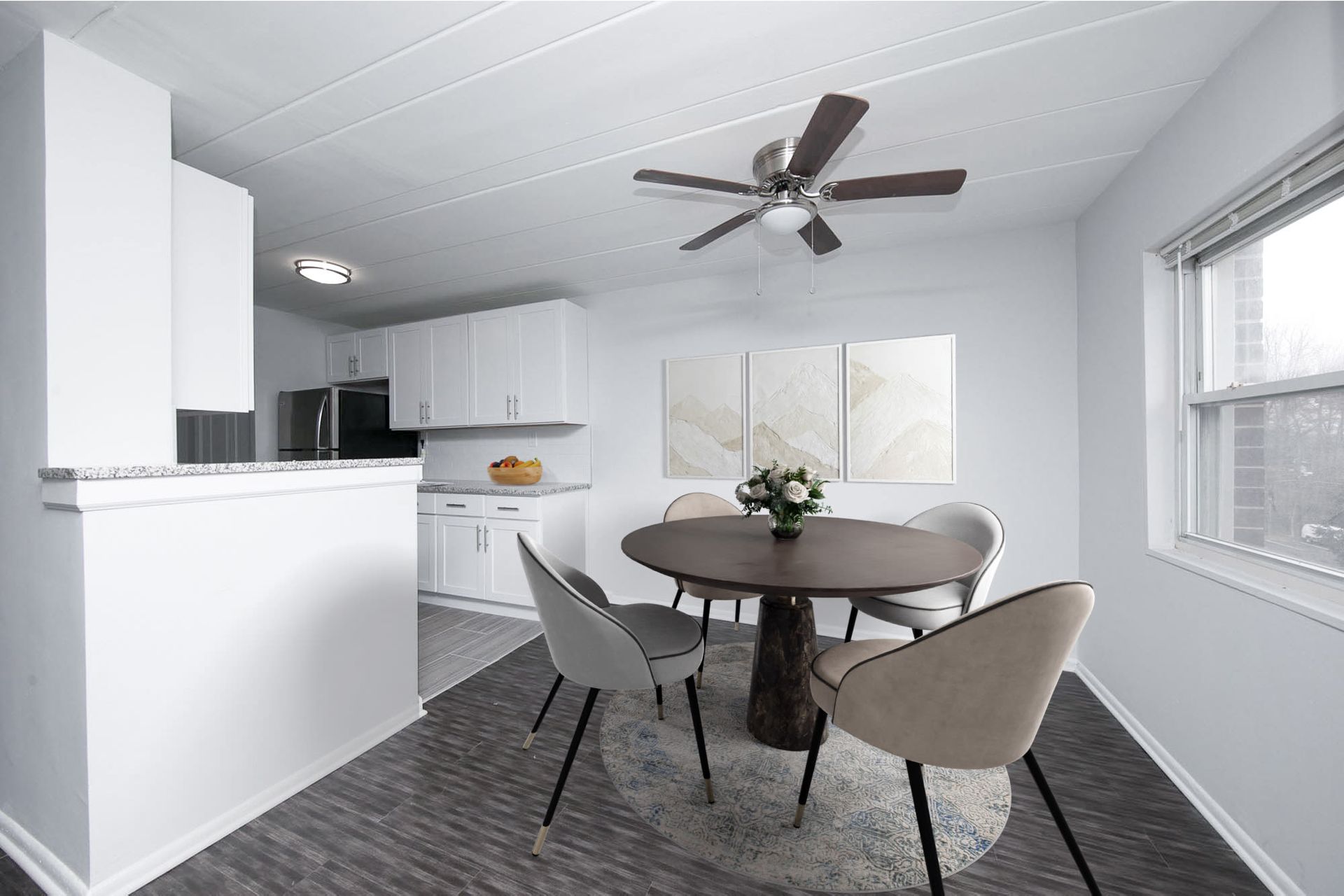 Open-plan kitchen and dining area in a modern apartment with a round table and four upholstered chairs.