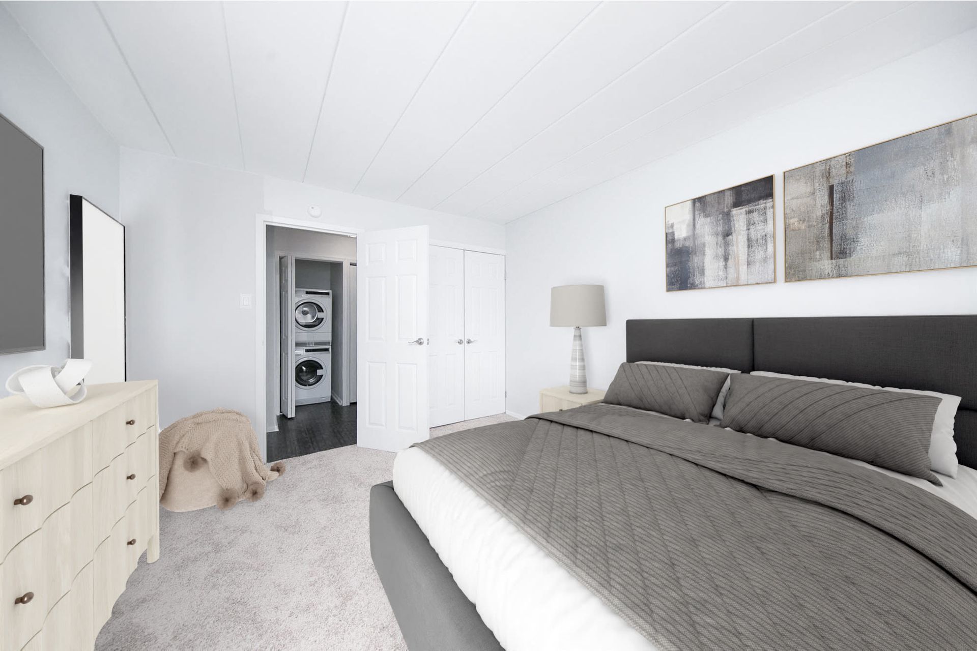 Bedroom with a large bed, dresser, and a visible laundry closet with stacked washer/dryer.