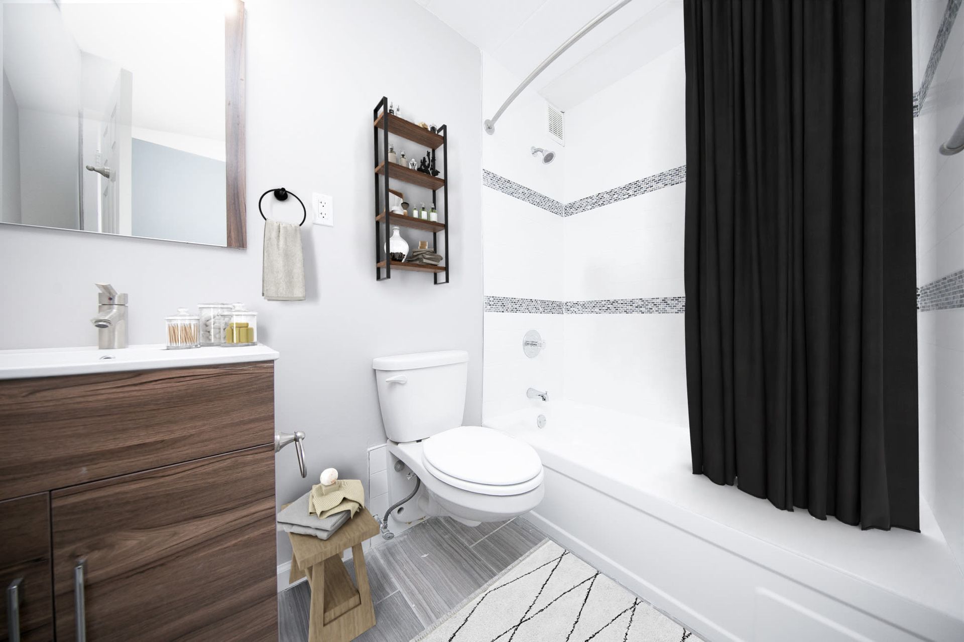 Modern apartment bathroom with vanity, toilet, and bathtub/shower with a black curtain.