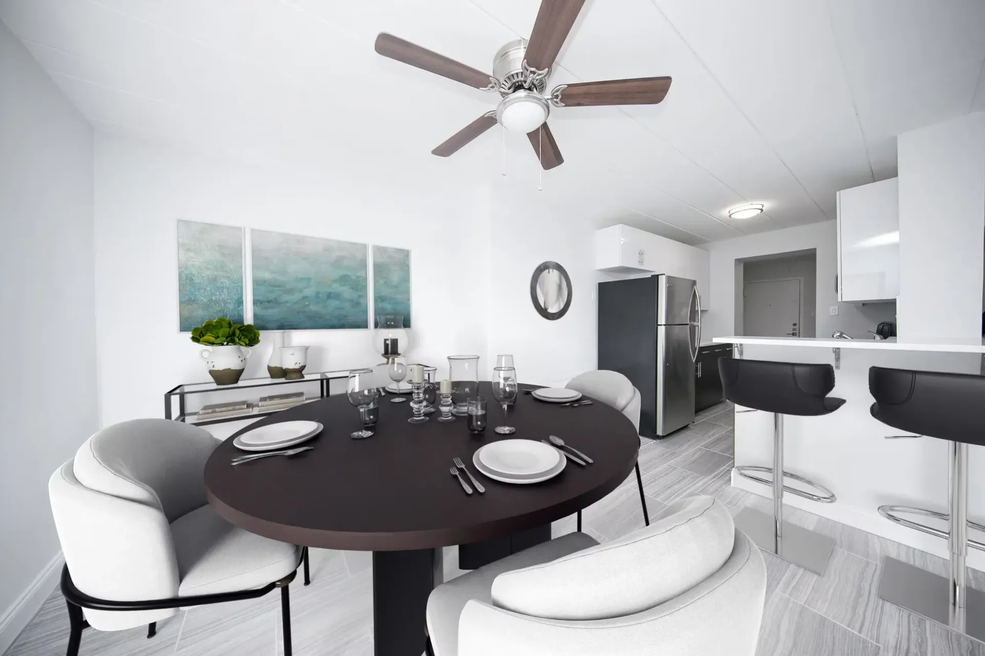 Modern dining and kitchen area with dark round table, chairs, and a bar counter.