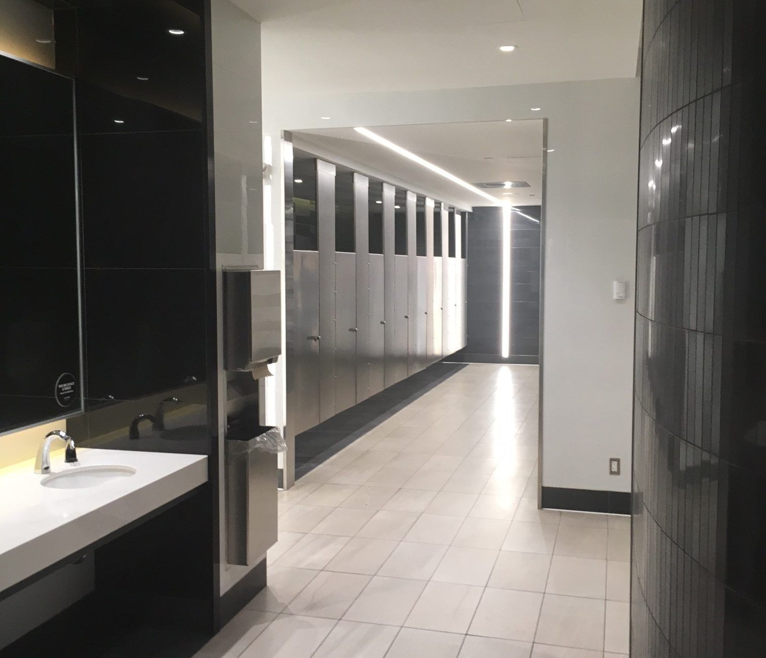 Un long couloir dans des toilettes publiques avec un lavabo et des miroirs