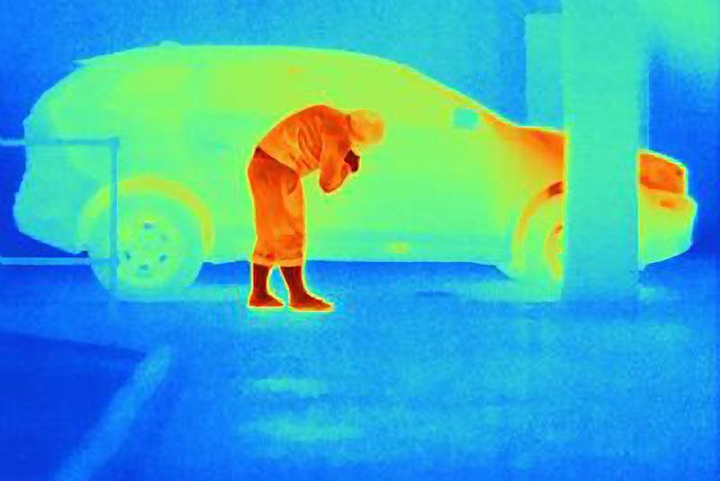 Burglar looking into car while being detected by FLIR.