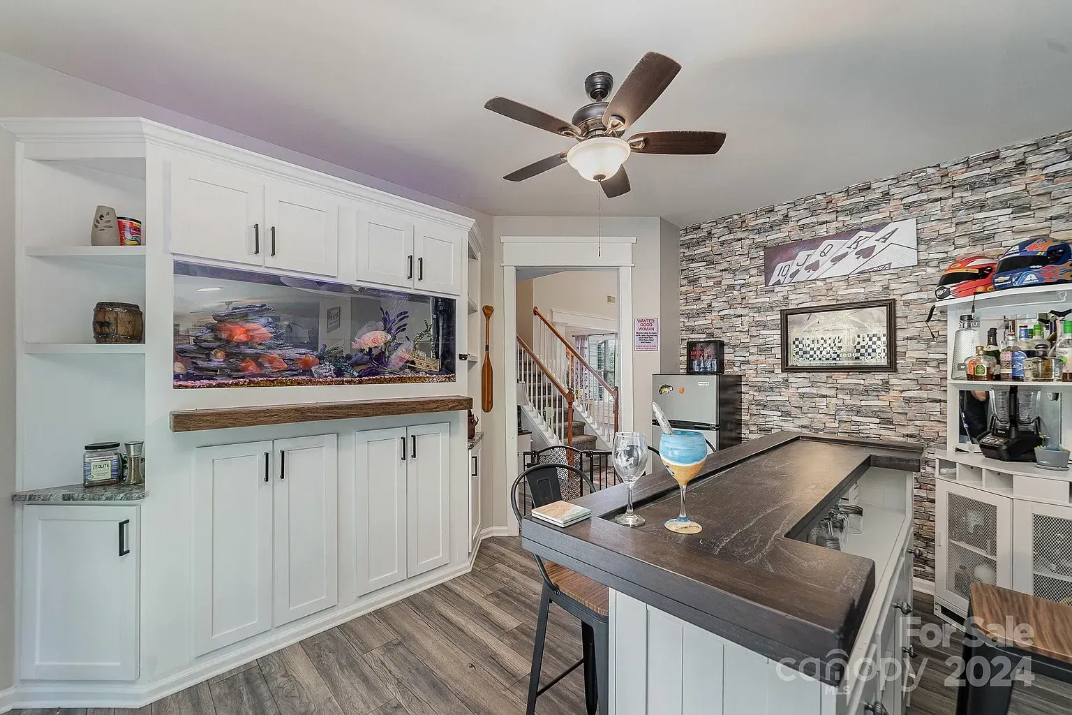 Home bar with aquarium, stone accent wall, and wood bar top.