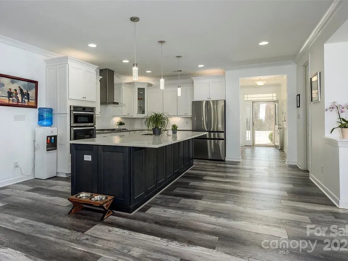 Modern kitchen with a large island, stainless steel appliances, and wood-look flooring.