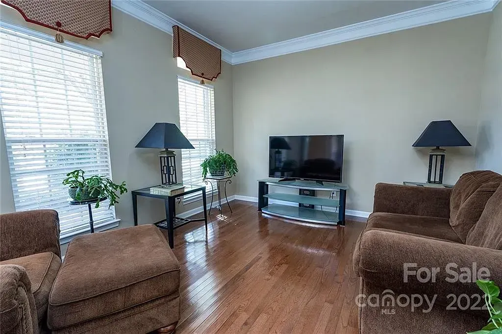 Living room with brown furniture, TV, lamps, and hardwood floors.