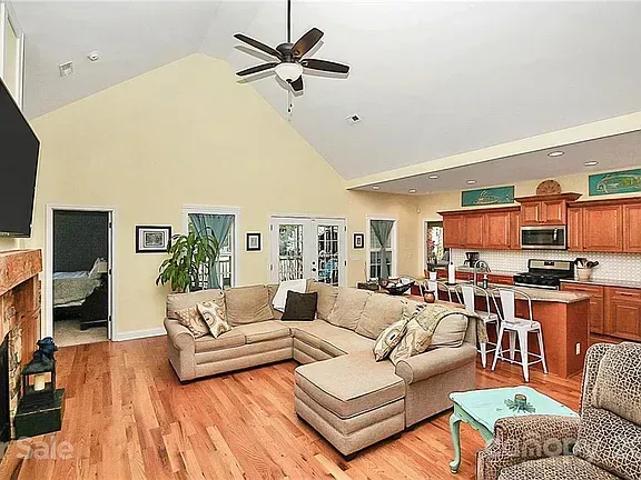 Spacious living room with vaulted ceiling, open kitchen, sectional sofa, and hardwood floors.