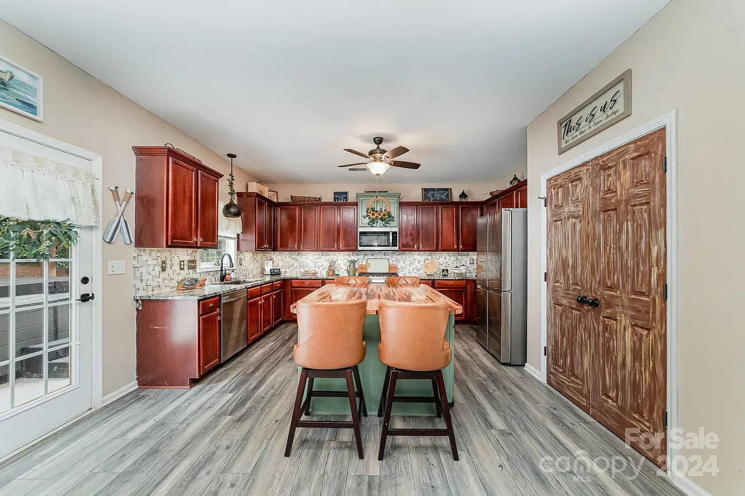 Spacious kitchen with wooden cabinets, island with seating, and stainless steel appliances.