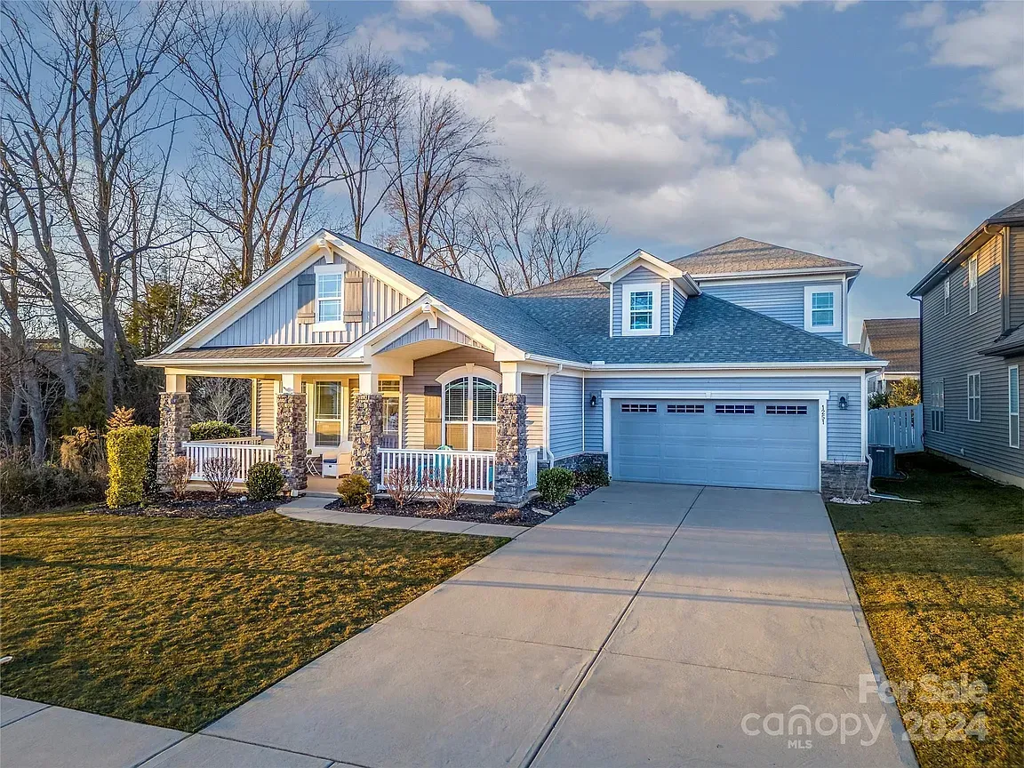 Blue house with a two-car garage, front porch, and lawn on a sunny day.