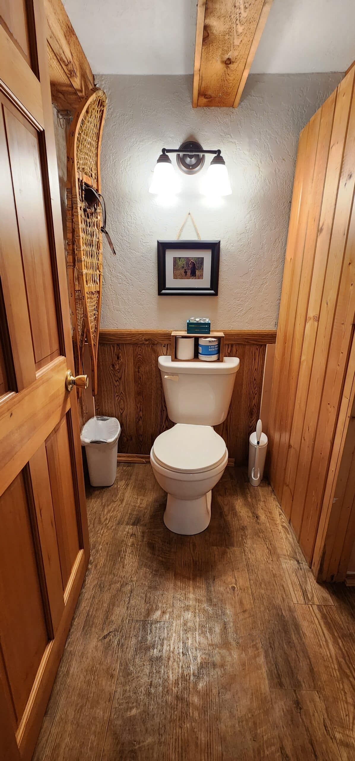 A bathroom with a toilet , sink and trash can.