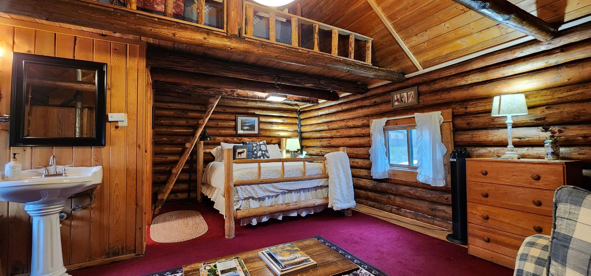 A log cabin with a bed , sink , dresser and stairs.